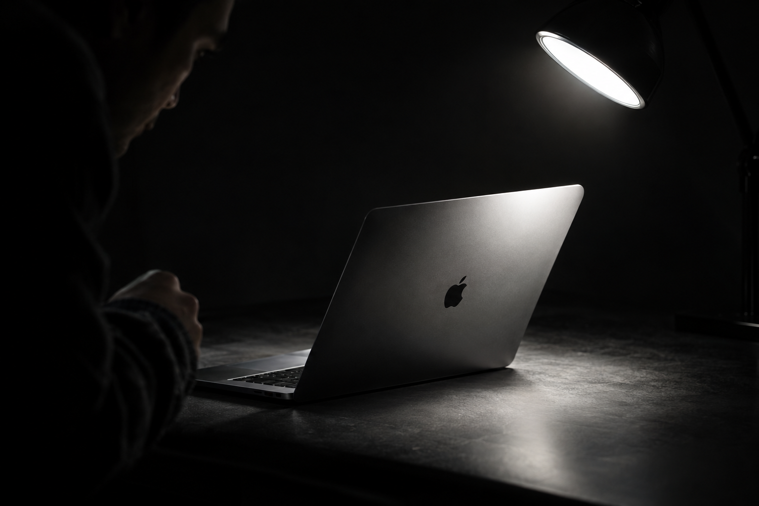 Close-up of a metallic laptop lid at a low angle showing light surface scratches and a small scuff near one corner