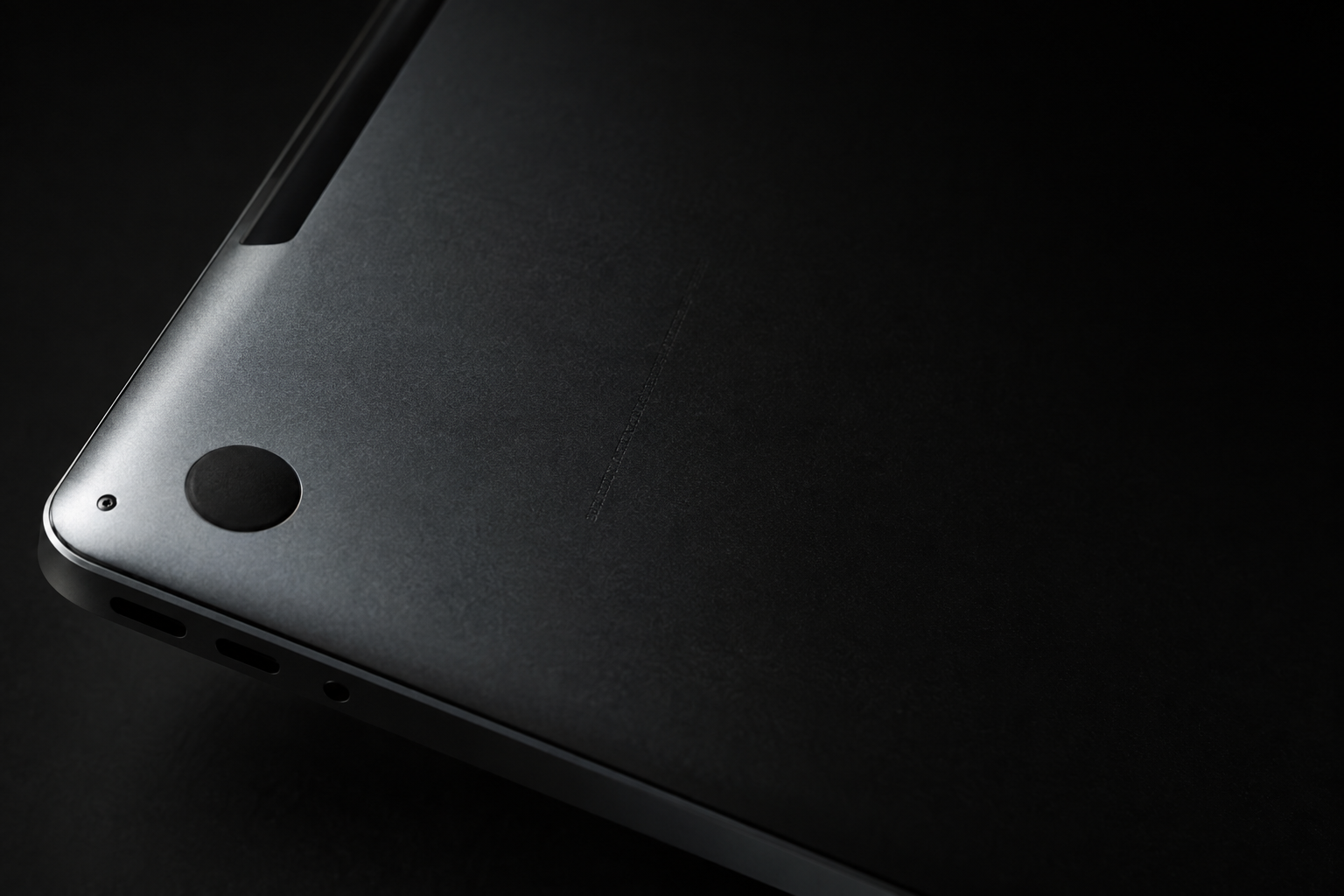 Close-up macro of the regulatory text and serial marking etched into the aluminum underside of a MacBook on a soft gray backdrop