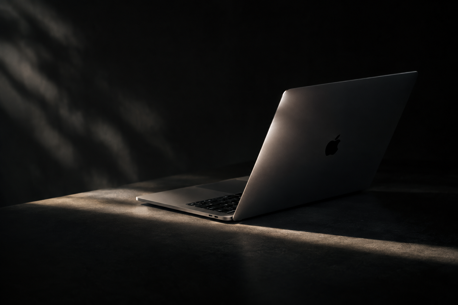 A closed laptop next to a simple round clock shape on a soft gray background