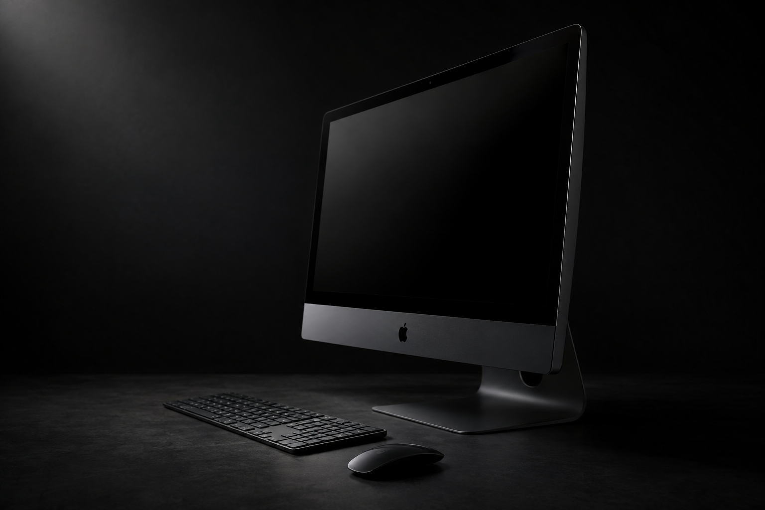 A dark-gray all-in-one desktop computer with a large display on a dark studio background